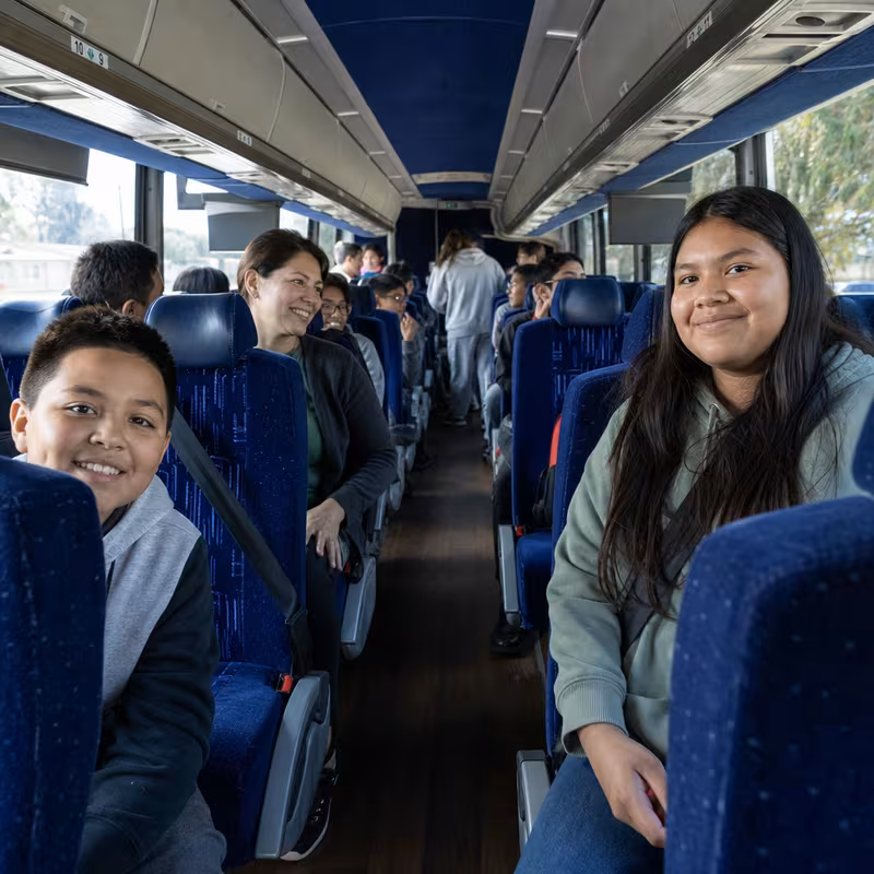 Group boarding a white charter bus for School Transportation transportation in Sioux Falls