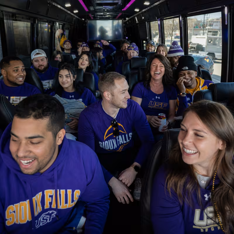 Group boarding a white charter bus for Sporting Event Transportation transportation in Sioux Falls